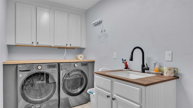 clothes washing area with separate washer and dryer, sink, and cabinets