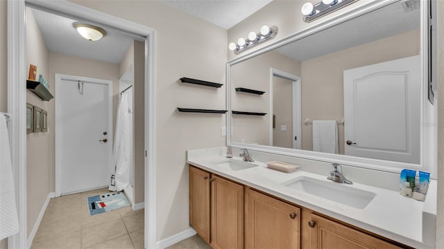 bathroom with tile patterned flooring, vanity, and a textured ceiling