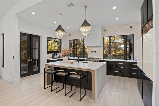 kitchen with a kitchen island with sink, hanging light fixtures, a healthy amount of sunlight, and sink