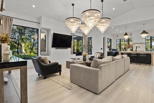 living room with light hardwood / wood-style flooring, lofted ceiling, and a notable chandelier