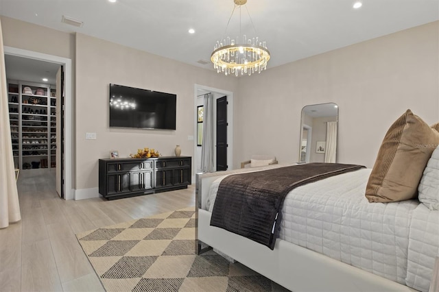 bedroom with light wood-type flooring, a closet, a walk in closet, and an inviting chandelier