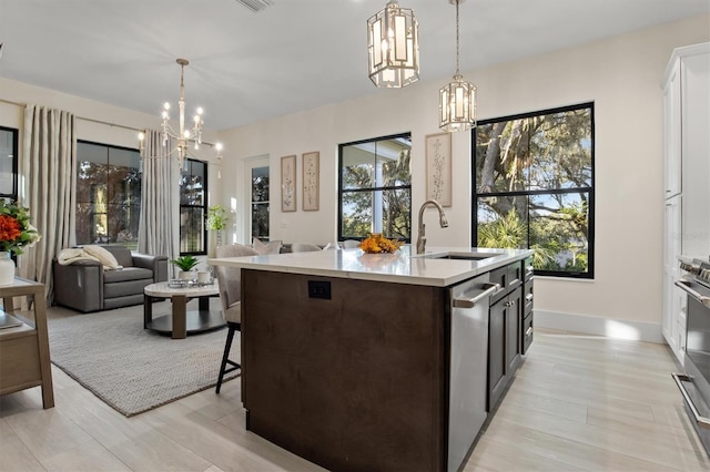 kitchen featuring hanging light fixtures, light hardwood / wood-style floors, sink, and dishwasher