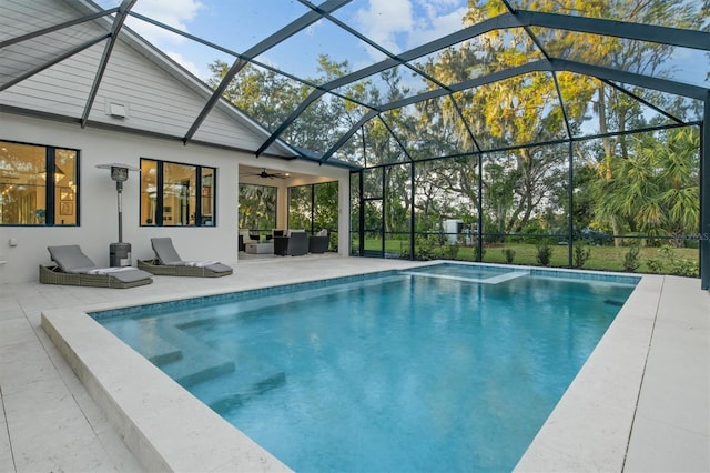 view of pool with an outdoor living space, ceiling fan, glass enclosure, and a patio area