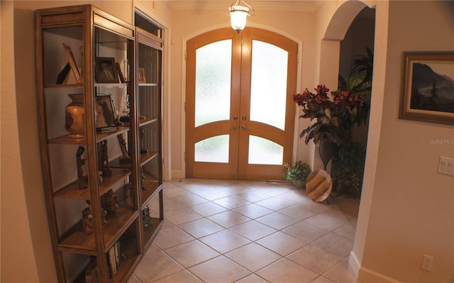 tiled foyer with crown molding and french doors