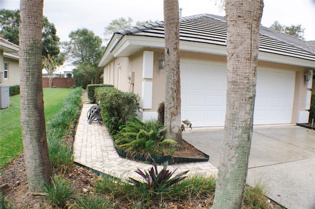 108 Lake Region Blvd N, Winter Haven, FL 33881 - view of side of home featuring stucco siding, a garage, driveway, a tiled roof, and fence