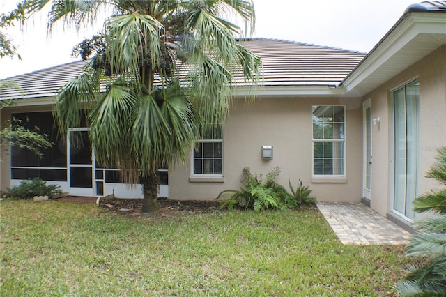 108 Lake Region Blvd N, Winter Haven, FL 33881 - view of side of home with stucco siding, a lawn, and a tiled roof