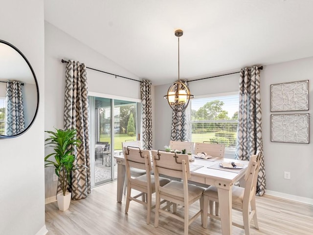 dining room with light wood-type flooring, a notable chandelier, and vaulted ceiling