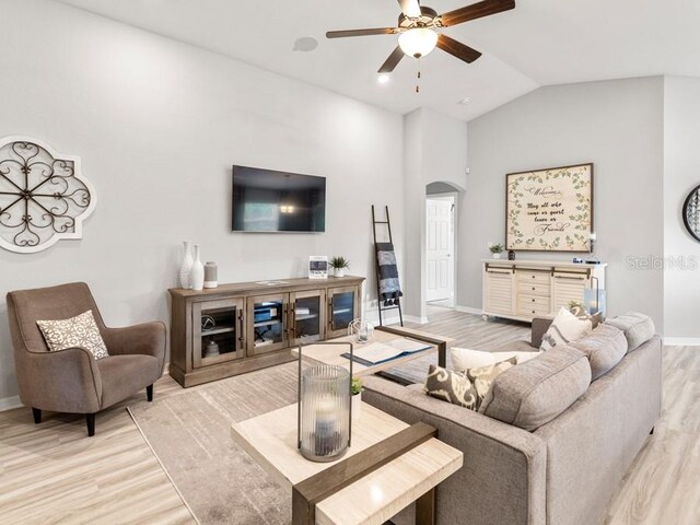 living room featuring light wood-type flooring, ceiling fan, and vaulted ceiling