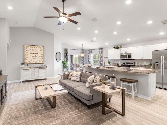 living room with light hardwood / wood-style floors, ceiling fan, and lofted ceiling