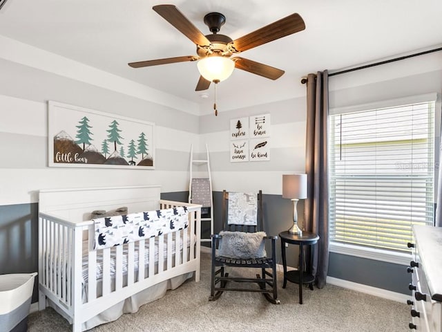 bedroom featuring a nursery area, carpet floors, multiple windows, and ceiling fan