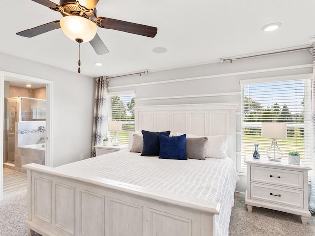 bedroom featuring light carpet, multiple windows, ceiling fan, and connected bathroom