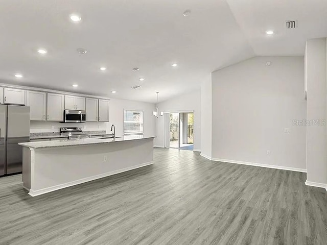 kitchen with a sink, an island with sink, light wood-style flooring, baseboards, and appliances with stainless steel finishes