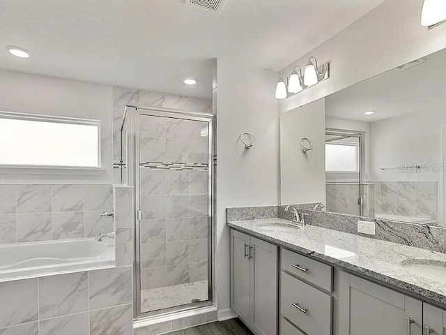 full bath featuring a shower stall, a garden tub, a wealth of natural light, and a sink