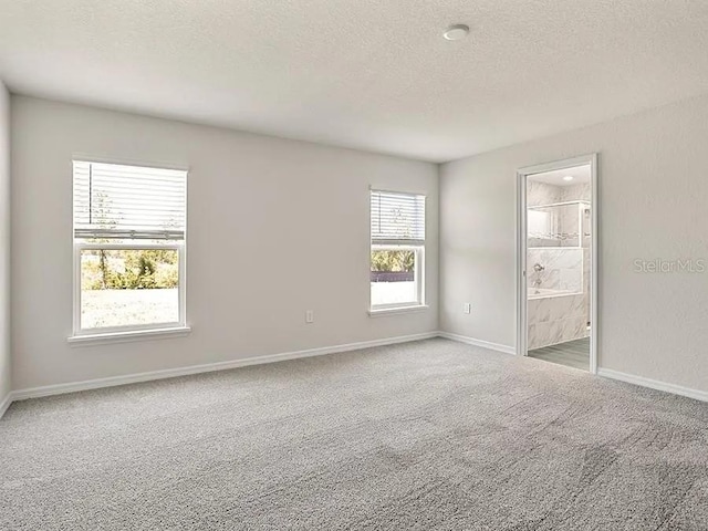 unfurnished bedroom featuring baseboards, carpet flooring, a textured ceiling, and ensuite bathroom