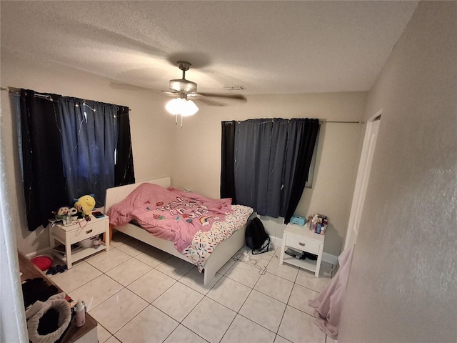 bedroom featuring a textured ceiling, light tile patterned floors, and ceiling fan