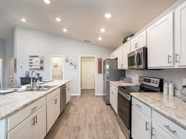 kitchen with white cabinetry, sink, appliances with stainless steel finishes, lofted ceiling, and light wood-type flooring