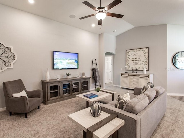 carpeted living room with ceiling fan and vaulted ceiling