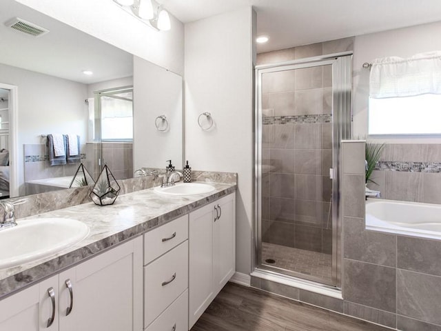 bathroom featuring vanity, plus walk in shower, a wealth of natural light, and wood-type flooring