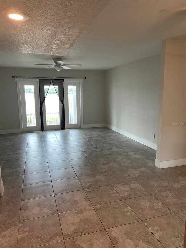 empty room with ceiling fan and a textured ceiling