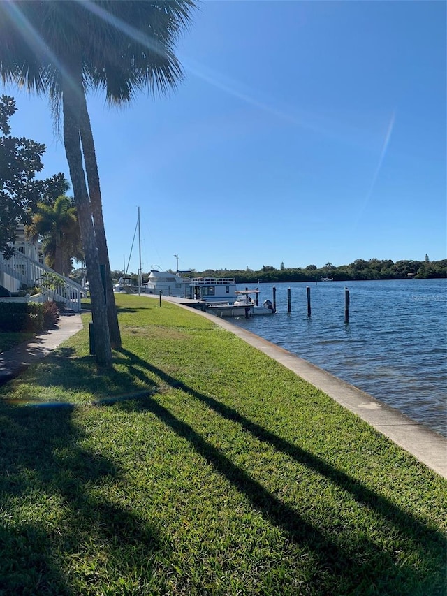 view of dock with a lawn and a water view