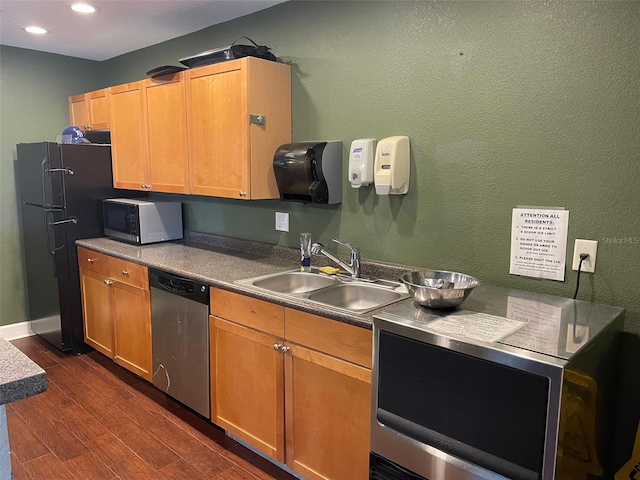 kitchen with dishwasher, black refrigerator, dark wood-type flooring, and sink