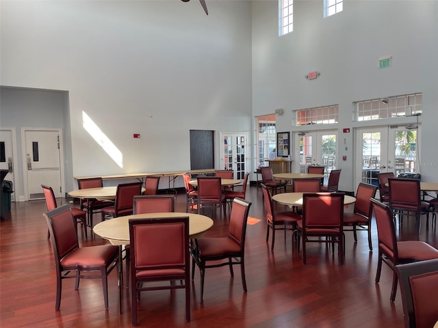 dining space featuring a wealth of natural light, french doors, a towering ceiling, and dark wood-type flooring