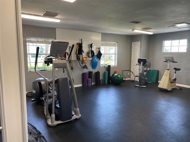 workout area featuring a wealth of natural light and a textured ceiling