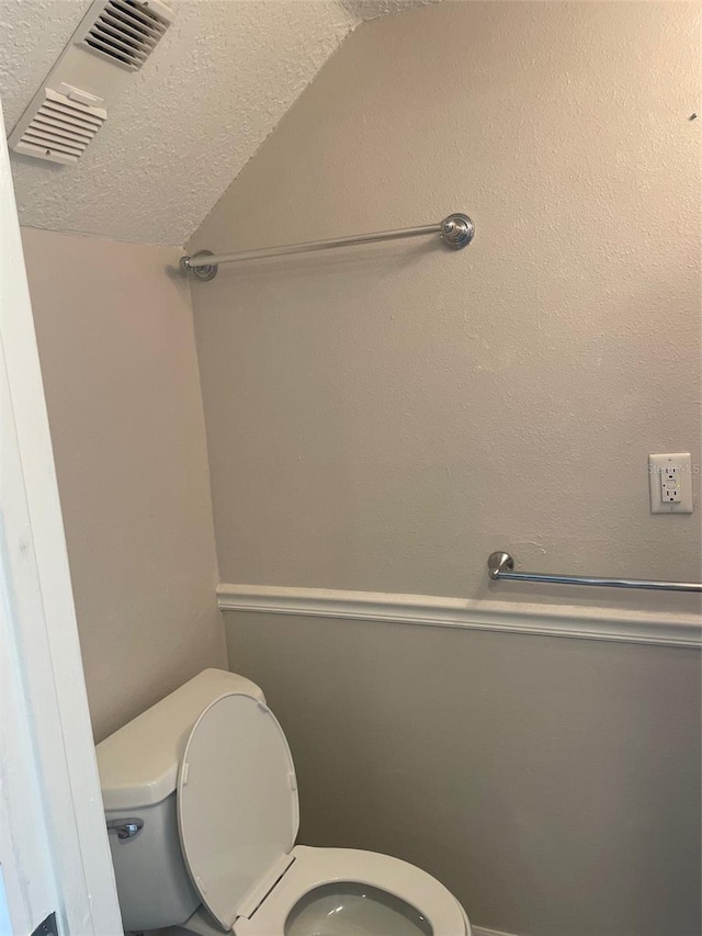 bathroom with lofted ceiling, a textured ceiling, and toilet