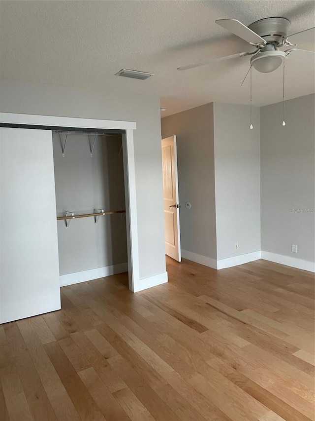 unfurnished bedroom with ceiling fan, light hardwood / wood-style floors, a textured ceiling, and a closet