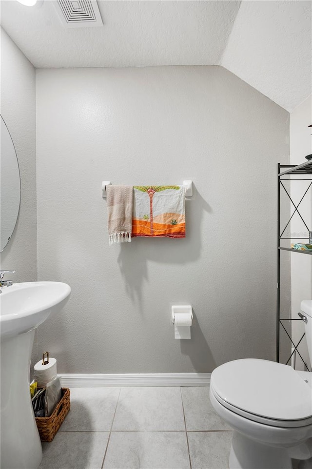 bathroom featuring toilet, lofted ceiling, sink, and tile patterned flooring