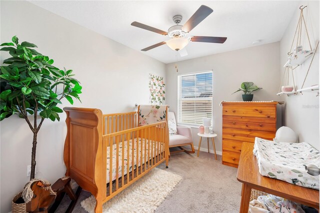 bedroom featuring carpet, ceiling fan, and a crib