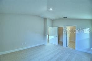 unfurnished bedroom featuring lofted ceiling and carpet flooring