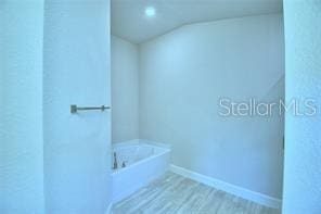 bathroom with hardwood / wood-style flooring and a washtub