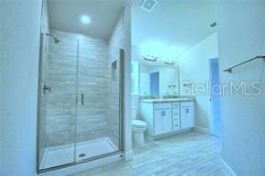 bathroom with vanity, toilet, and a shower with door