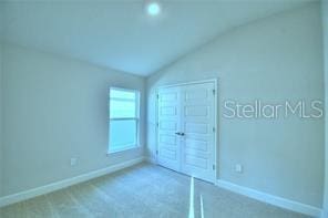 unfurnished bedroom with carpet floors, lofted ceiling, and a closet