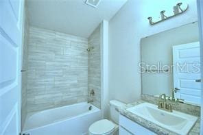 full bathroom with vanity, tiled shower / bath combo, and toilet