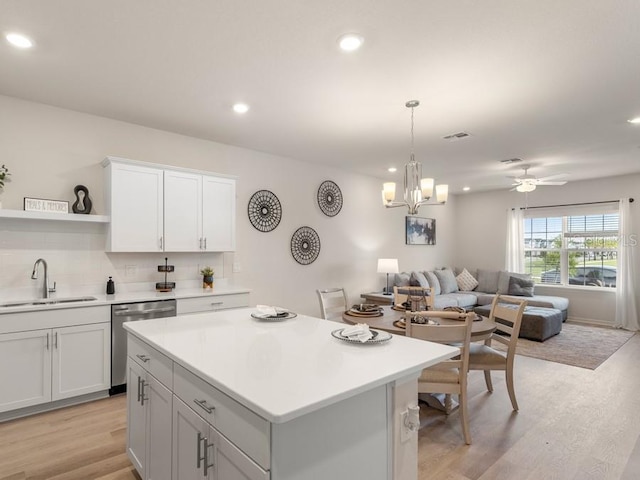 kitchen with white cabinets, stainless steel dishwasher, light hardwood / wood-style flooring, and sink