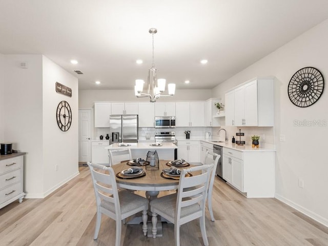 dining space featuring light wood-type flooring, sink, and a chandelier