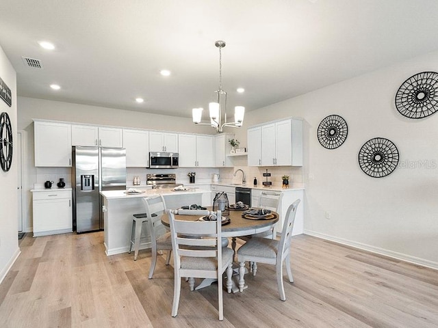 dining area featuring light wood-type flooring, sink, and a notable chandelier