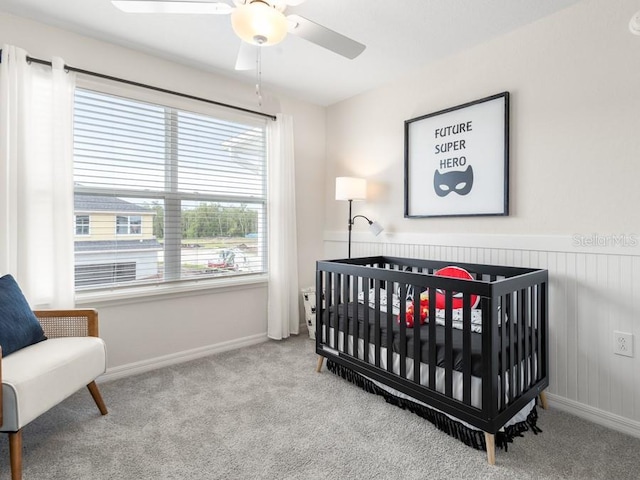 bedroom featuring a crib, ceiling fan, and light colored carpet