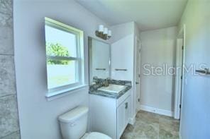 bathroom featuring vanity, a healthy amount of sunlight, and toilet