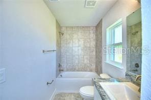 full bathroom featuring toilet, tiled shower / bath combo, and vanity