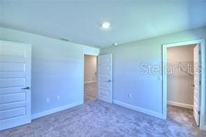 unfurnished bedroom with a closet, a walk in closet, and carpet