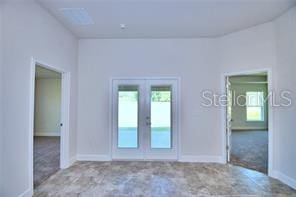 carpeted spare room with french doors and a healthy amount of sunlight