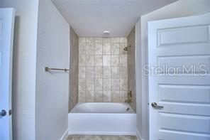 1580 Leamington Ln, Winter Haven, FL 33884 - bathroom featuring washtub / shower combination and baseboards