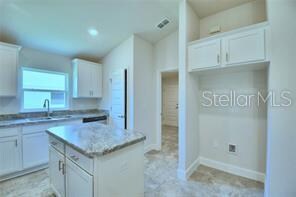 kitchen featuring white cabinets, sink, and a kitchen island