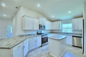 kitchen featuring a center island, vaulted ceiling, white cabinets, kitchen peninsula, and appliances with stainless steel finishes