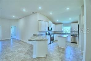 kitchen with white cabinetry, kitchen peninsula, stainless steel appliances, and a center island