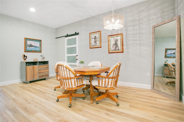 dining area with wood-type flooring, a barn door, and a notable chandelier