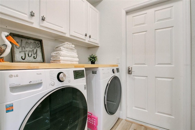 laundry area with cabinets, washing machine and dryer, and light wood-type flooring